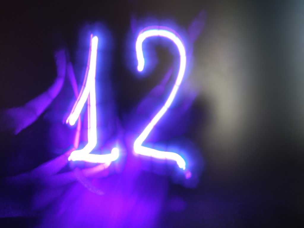 shutterstock 2147196669 glowing purple neon number 12 twelve on a dark matte glass background